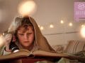 Junge unter Decke mit Taschenlampe Buch lesen